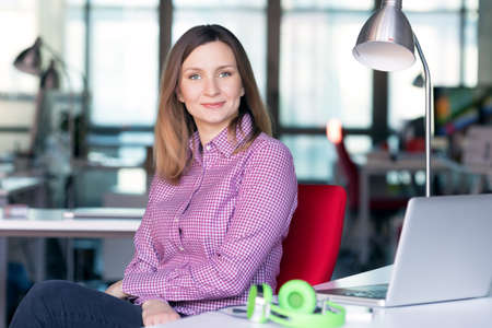 Charismatic Business Lady in casual clothing sitting at Office Tableの写真素材