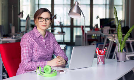 Charismatic Business Lady in casual clothing sitting at Office Tableの写真素材