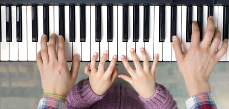 Piano Keyboard top View and Hands of Child and Motherの写真素材