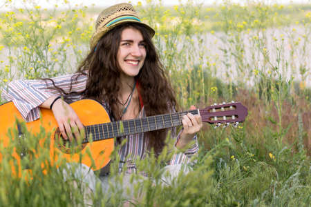 Cute female Musician sitting on green Grassの写真素材