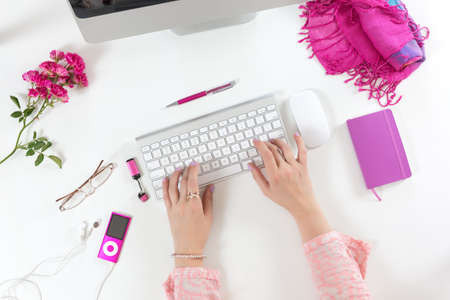 Lady working on Computer White Desk with red and pinkの写真素材