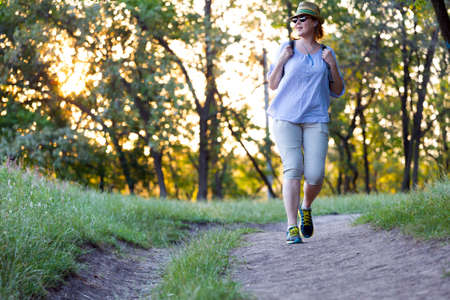 Carefree Woman walking on Forest Trail at Sunsetの写真素材
