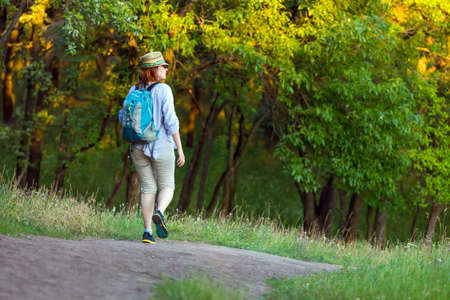 Woman walking on Trail in wild Forest at Sunset lightの写真素材