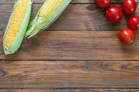 Summer Harvest Composition on Wooden Background Corn and Tomatoの写真素材