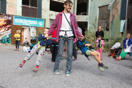 Father swings around little children hanging on climbing harnessのeditorial素材