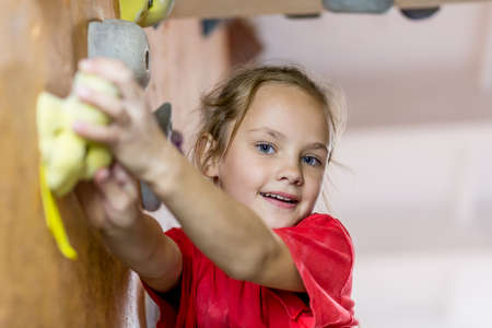 Junior Climber hanging on holds on climbing wallのeditorial素材
