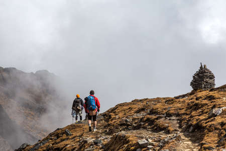 Two People walking on Mountain Slope towards stone Towersの写真素材