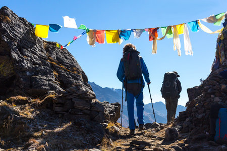 Silhouettes of Hikers crossing Mountain Pass under Buddhist Flagsの写真素材