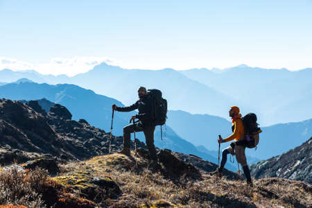 Silhouettes of two Hikers in front of Morning Mountains Viewの写真素材