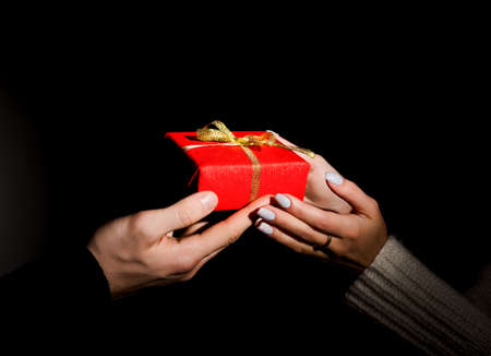 Male and female hands passing decorated gift on blackの写真素材