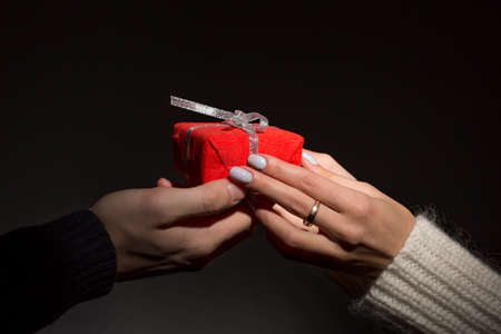 Male and female hands passing decorated gift on blackの写真素材