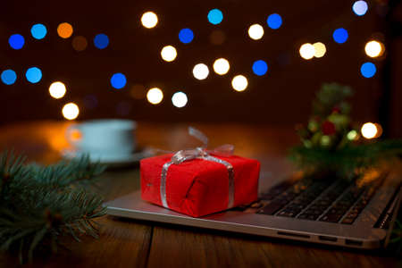 Laptop and red Gift Box on wood Table with Christmas Lightsの写真素材