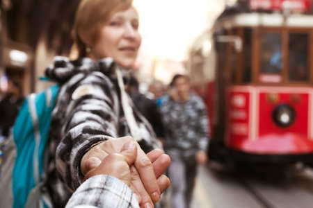 Joyful Girl pulling her Husband toward Tram focus on the handsの写真素材