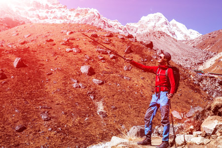 Young male Mountain Hiker pointing forward with walking Stickの写真素材