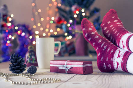 Person enjoying Holiday Eve with gift and hot drinkの写真素材