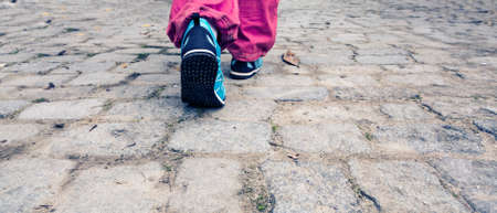 Feet of Person walking on old paved Roadの写真素材