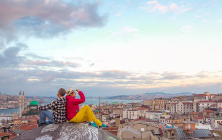 Man and Woman sitting on Roof City Building at sunset