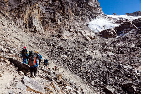 Group of Mountain Climbers walking on rocky slope toward Passの写真素材