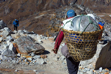 Nepalese Porter carrying Basket with rural household goodsの写真素材