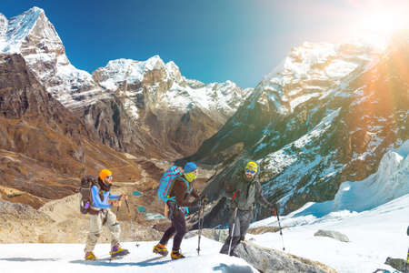 Group of Friends in Mountains traversing Glacier towards rising Sunの写真素材