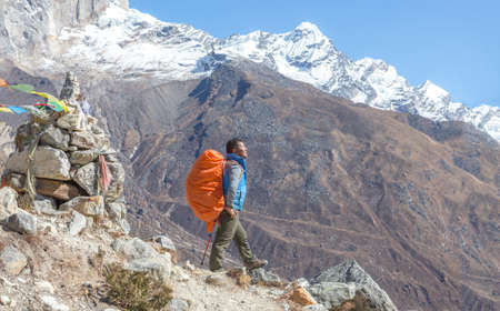 Nepalese Sherpa Mountain Guide staying on Footpath and buddhist flagsの写真素材
