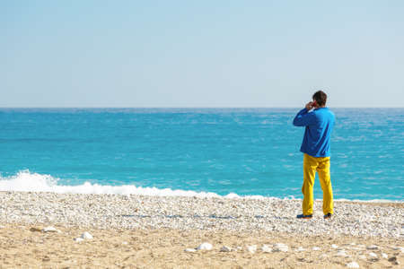 Man in casual Clothing talking on Phone at Sea Beachの写真素材
