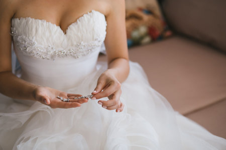 Elegant bride holding silver earrings. Tender hands with jewelry.の写真素材