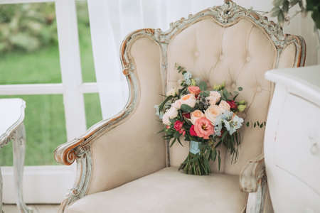 Beautiful spring wedding bouquet of roses and eucalyptus on a beige vintage armchair with a blue ribbonの写真素材