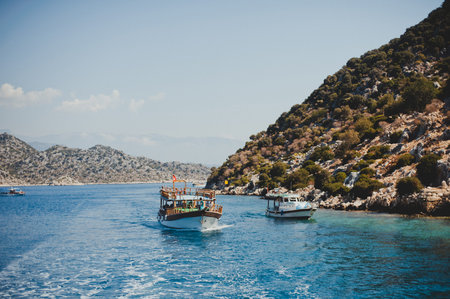 Boats sail in the summer in the Mediterranean Sea with azure water among the mountains and hills, a...