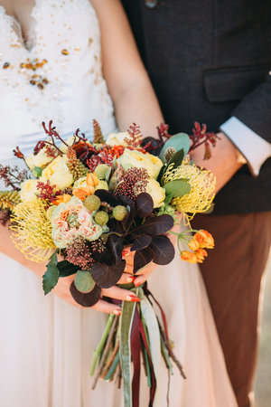 Autumn fashion wedding bouquet in hands of the bride and groom. Vertical
