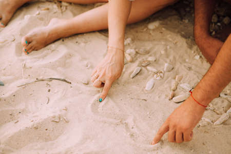 Man and woman draw their hands on the heart in the sand. Horizontalの写真素材