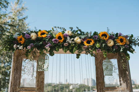 Wooden wedding arch in Provence style decorated with flowers, sunflowers and other summer flowers. Horizontalの写真素材