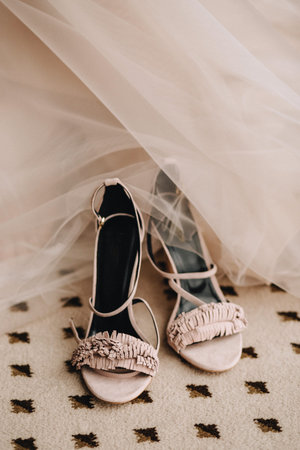 Pink elegant shoes of the brides sandals on the floor next to the wedding dressの写真素材