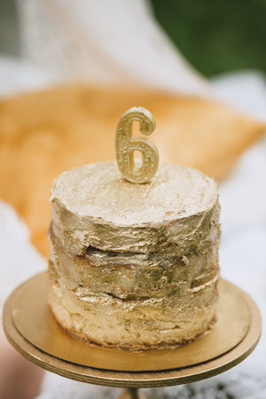 Delicious birthday cake covered with golden food paint and with a candle in the form of a number...
