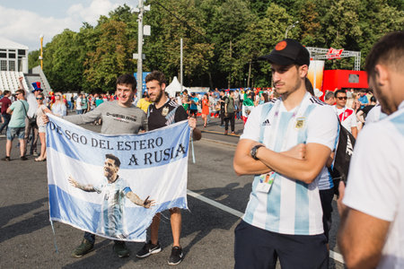MOSCOW, RUSSIA - JUNE 2018 Football fans are photographed with the flag of Argentina on which is...
