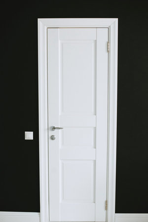 White beautiful door with platbands on a black background. Vertical