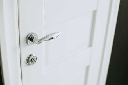 Chrome plated metal handle on white door. Horizontalの写真素材