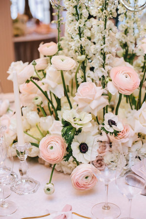 Luxurious flower arrangement of buttercups, white roses on a banquet table, along with candlesticks...