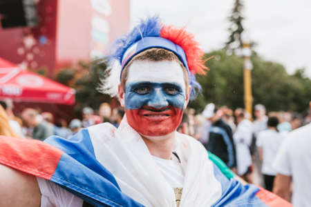 MOSCOW, RUSSIA - JULY 2018 Football fan face painted in the colors of the Russian flag and hat in the fan zone during the World Cupのeditorial素材