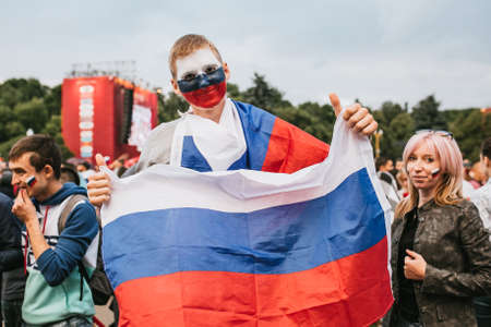 MOSCOW, RUSSIA - JULY 2018 A football fan with a face painted in colors of the Russian flag and with a headdress in the fan zone during the World Cupのeditorial素材