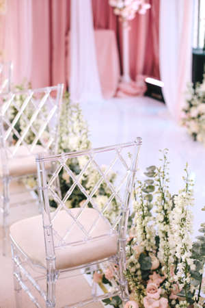 Transparent design chairs at the wedding ceremony decorated with white flowers. Verticalの写真素材