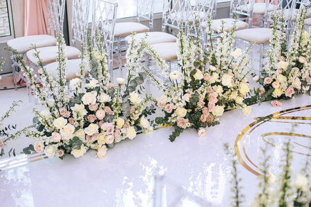 The white carpet for the wedding ceremony is decorated with flower compositions of roses, buttercup and bells with transparent chairs for guests. Horizontalの写真素材