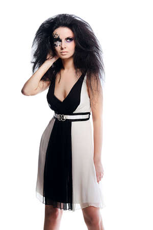 brunette woman in black and white dress with black hair and art make up on white backgroundの写真素材