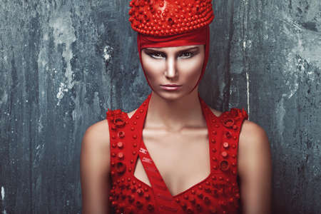 girl in red and concrete wall behindの写真素材