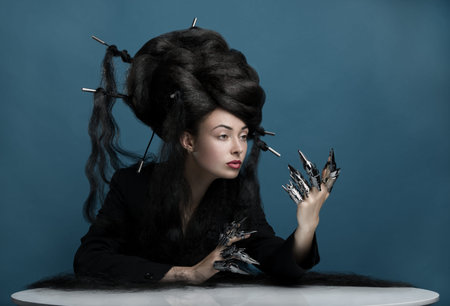 Gothic style shot of a woman with claw rings sitting at the table