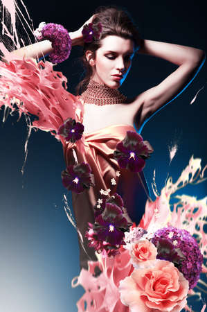 beautiful woman in long dress in blue light with flowers and splashの写真素材