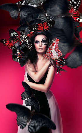 Woman with black hair and art make up and red butterfliesの写真素材