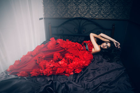 sexy woman in red dress on bedの写真素材