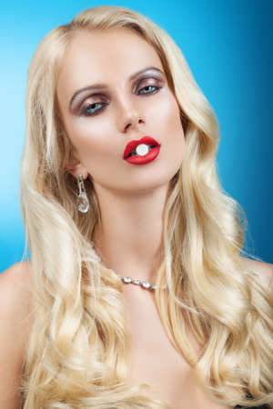 Woman with pill in mouth on blue backgroundの写真素材