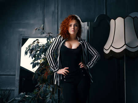 Ginger girl at home next to the mirror, lamp and homeflowerの写真素材